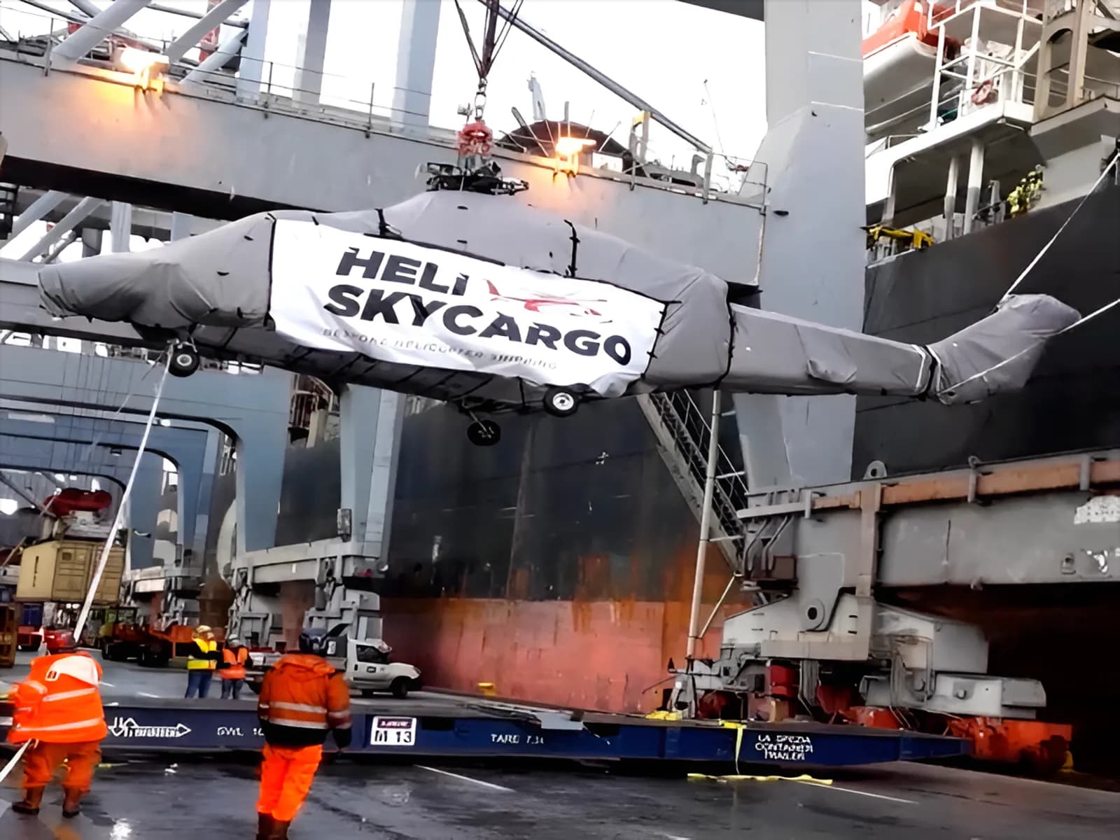 Wrapped helicopter being lifted by ship-side crane